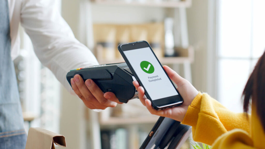 Retail merchant accepting e-wallet payment via QR at checkout counter